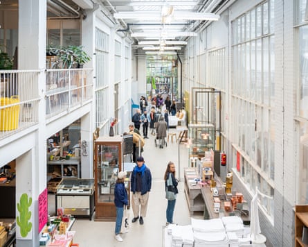 People browsing in a two-storey exhibition space, which is painted white with lots of glass.