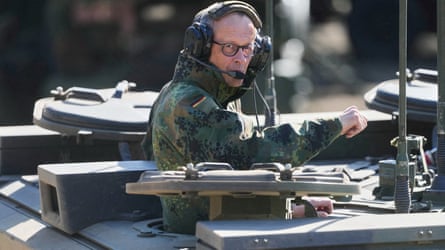 Friedrich Merz is in an armoured fighting vehicle, wearing a headset