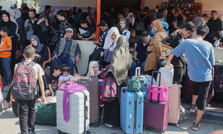 Crowds of people stand around their suitcases