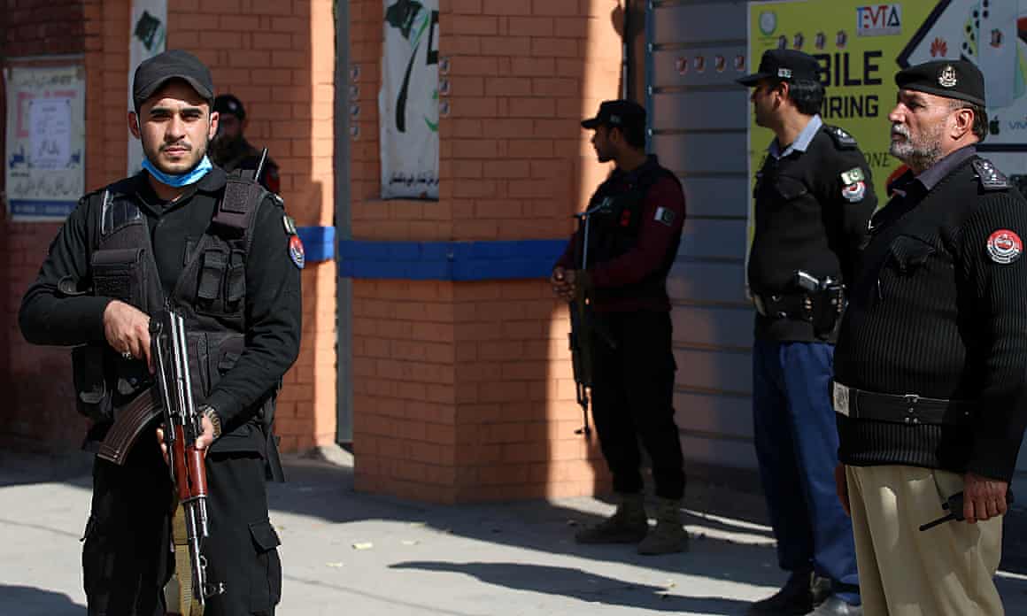 Pakistani security officials stand guard outside a polling station in Peshawar.