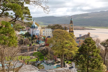 Portmeirion’s colourful hillside village with ornate architecture, including a pink domed building and yellow tower with turquoise benches