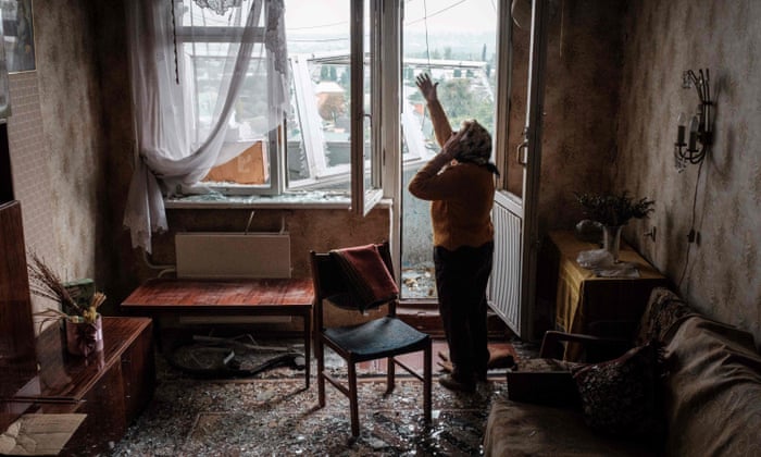 lyubov Prokofjevna, 85, speaks on the phone in her damaged apartment in Kharkiv.