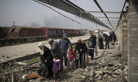 Iraqi civilians flee through a destroyed train station during fighting between Iraqi security forces and Islamic State militants on the western side of Mosul, on 19 March 2017. 