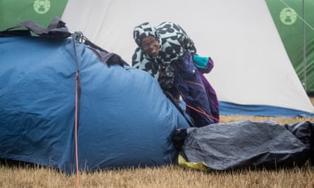 A festival goer packs up her tent in the wind and rain at Camp Bestival.