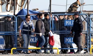 A man is escorted by Turkish police after arriving by ferry at Dikili harbour