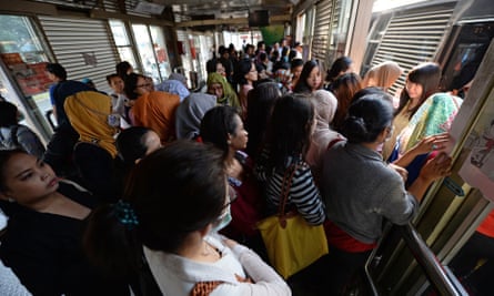 Morning commuters wait to board a TransJakarta bus at a station