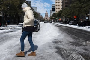 A woman walks across the snow covered street near the Texas state capitol Tuesday, Feb. 16, 2021, in Austin, Texas.