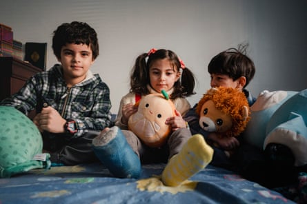 three children on a bed with cuddly toys