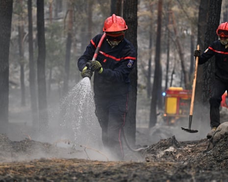 A firefighter sprays water after a wildfire in the region of the Fontainebleau forest, south of Paris, France.
