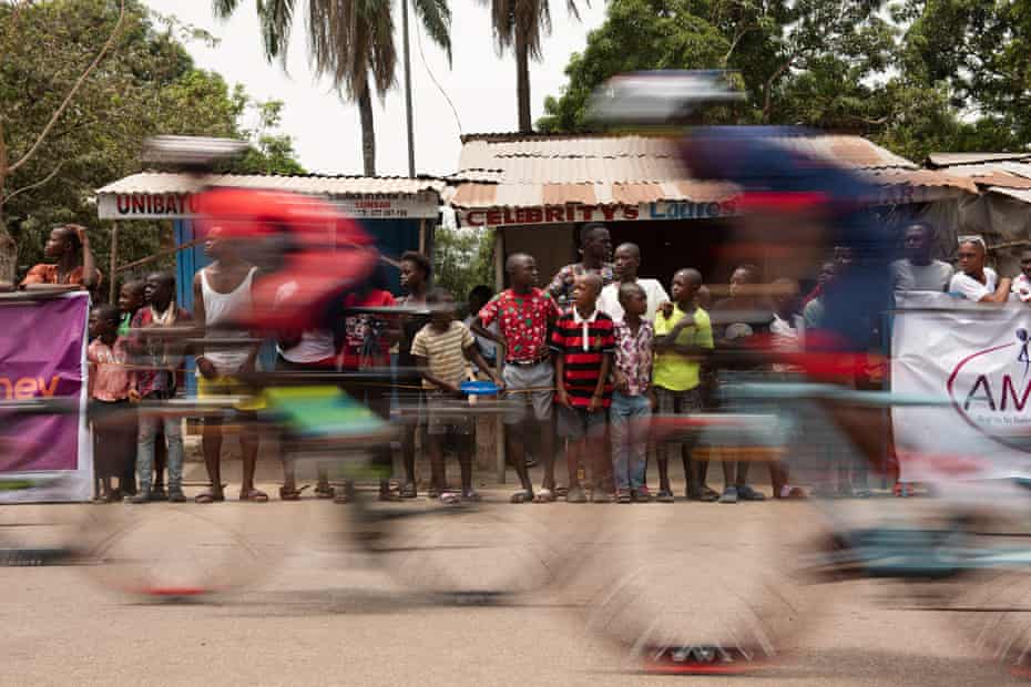 The peloton flies past spectators in Lunsar.