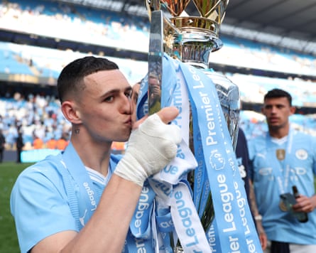 The Manchester City player Phil Foden kisses the Premier League trophy.