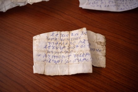 A piece of paper with blue biro writing on it. The note has many fold marks but is now spread out on a table.