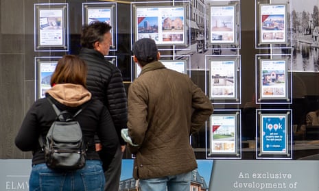 Three people look at property notices in an estate agent’s window in Maidenhead, Berkshire.