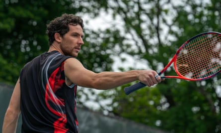 Josh O’Connor holding a tennis racket and wearing a vest top