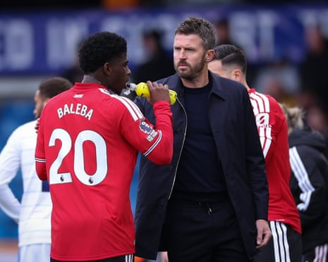 Michael Carrick (right) speaks with Carlos Baleba during the Premier League match between Leeds and Manchester United.