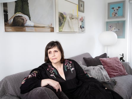 Paola Marra in a black dress on a sofa under paintings of humans and dogs
