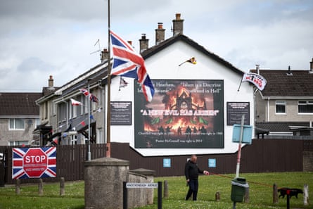 A man walks his dog in front of an anti-Islam mural, and an anti-immigration banner