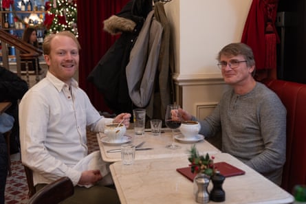 Rupert and Paul sitting at a restaurant table, smiling at the camera