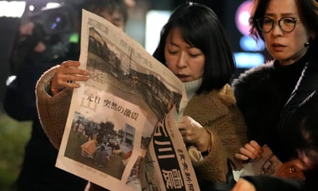 People in Tokyo read an extra edition of Yomiuri Shimbun newspaper reporting the earthquakes.