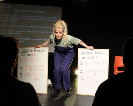 A white woman with blond hair and dungarees holds two white boards with notes on Golden Rewards and Golden Rules