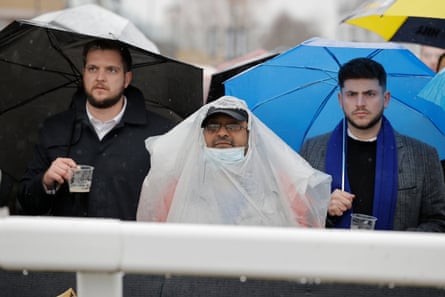 Racegoers watching in the pouring rain during racing on day two of the 2022 Cheltenham festival