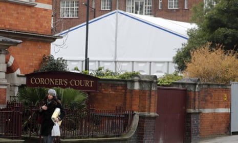 A woman walks past a tent being built to be used as a temporary morgue in London on 19 March.