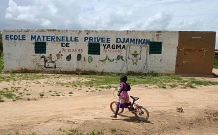 A girl rides her bicycle in the front of a school in the village of Yagma, north of Ouagadougou, on 17 September 2019.