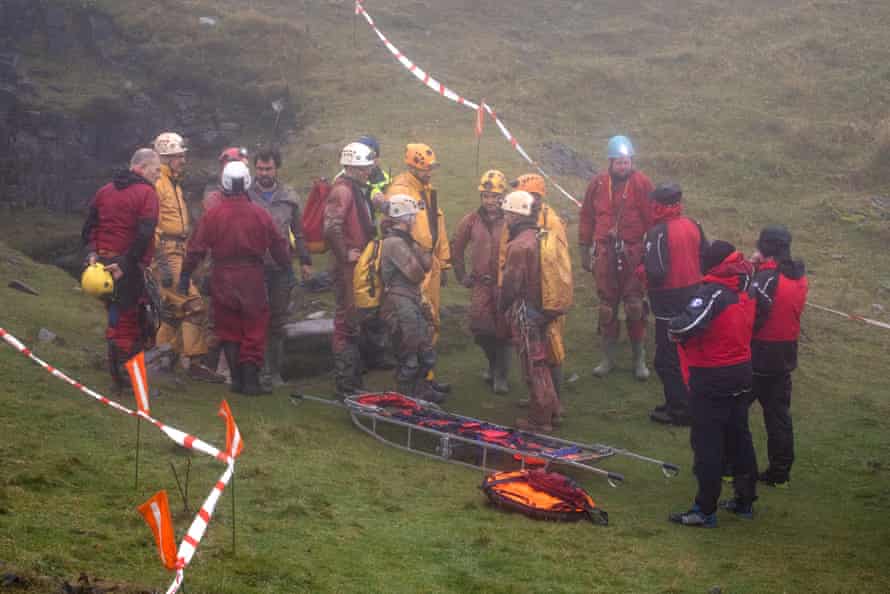 Rescuers emerge from the cave entrance after taking their turn in assisting the effort to bring back George Linnane from the cave network under Brecon Beacons