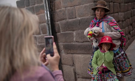 A Quechua woman and child have their photographs taken by a tourist for money in Cusco, Peru.