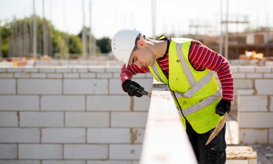 A workman lays concrete bricks