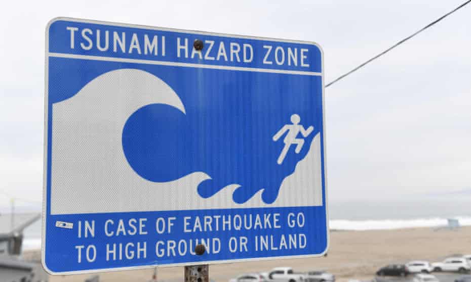 sign says 'tsunami hazard zone - in case of earthquake go to high ground or inland'