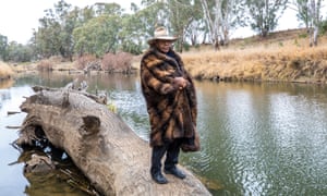 Peter Peckham of First Lesson Cultural Tours, standing on a log that rests by a river.