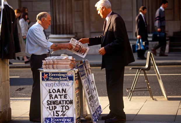 Picture of a man in a suit buying copy of the Evening Standard at a stall. The headline on the paper says 'Day of Crisis' and the stall billboard says 'Loan rate sensation - up to 15%'