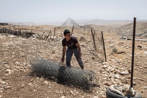 A young man rolls up a wire fence