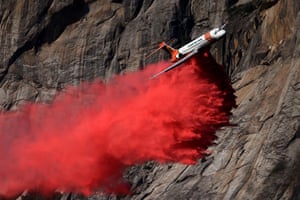 A low-flying plane drops bright red retardant