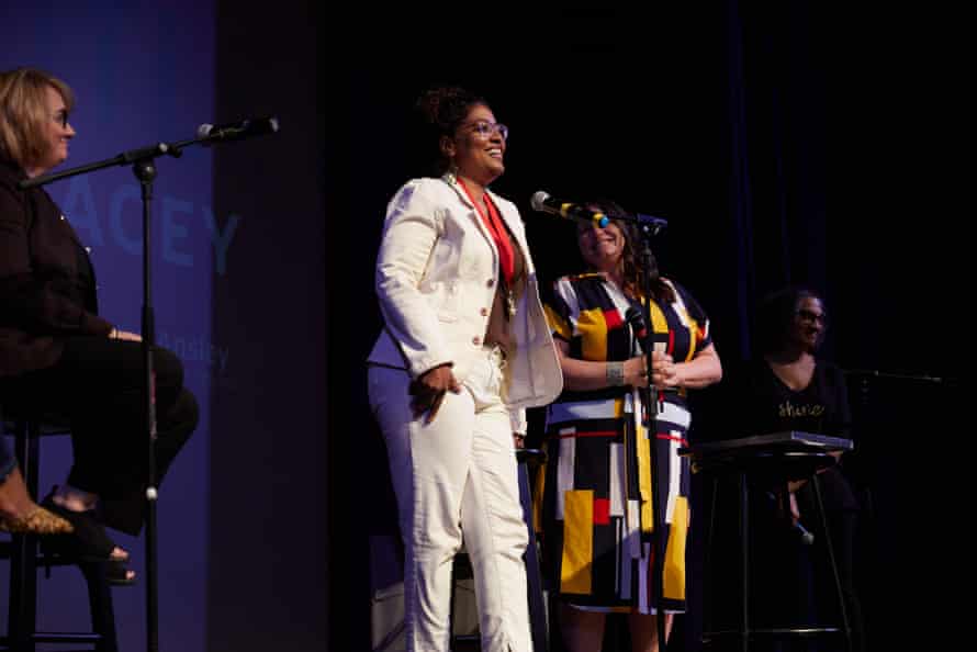 Woman in a white suit speaks on stage