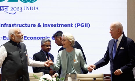 Ursula von der Leyen simultaneously clasps the hands of Narendra Modi (to her right) and Joe Biden (to her left) in front of a screen promoting the Partnership for Global Infrastructure Investment at India's G20 summit