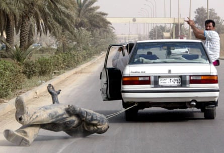 Iraqis drag a statue of Saddam Hussein behind their car in Baghdad in April 2003.