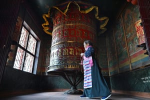 A woman spinning a large rotating drum covered in symbols