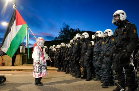 A protester waves a Palestine flag as policemen stand guard outside the Ullevaal Stadion before the World Cup qualifying match between Norway and Israel.
