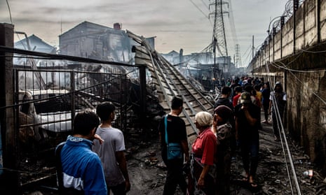 People look at burnt houses in a residential area in Plumpang, north Jakarta after a fire at the nearby depot.