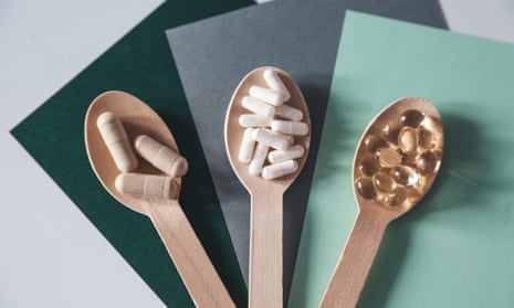 Three wooden spoons, with tan pills, white pills and clear, golden pills, respectively.
