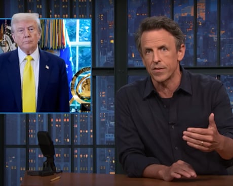 talk-show host gestures while speaking to the camera next to a picture of Donald Trump