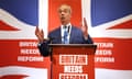 Nigel Farage, in a blue suit, left arm aloft before the union Jack, announcing he will stand as Reform UK candidate in Clacton, Essex, in the upcoming election