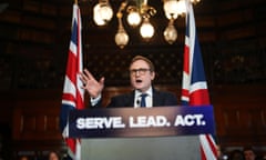 Tom Tugendhat, flanked by two union flags, speaks behind a lectern with the words 'Serve. Lead. Act' written on it