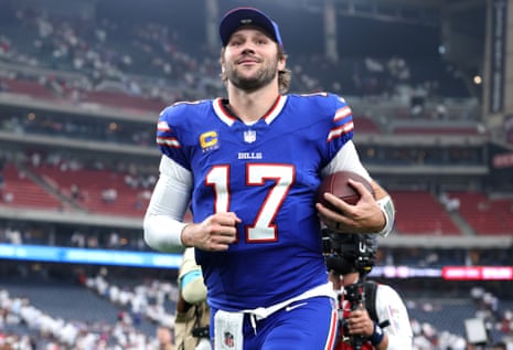 Josh Allen jogs off the field in his Bills jersey, holding a football
