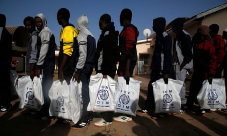Gambian migrants returning home from Libya carry bags from UN agency the International Organization for Migration.