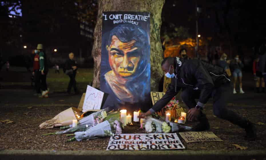 A man places a candle beneath a portrait of David Dungay during a protest against Aboriginal deaths in custody in Sydney last year. A NSW inquiry into Aboriginal deaths in custody has recommended sweeping reforms to the justice system.