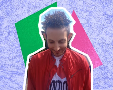 Man with a red jacket and a white I Love Londo T-shirt leans forward with a spiky, gold-sprayed hairstyle