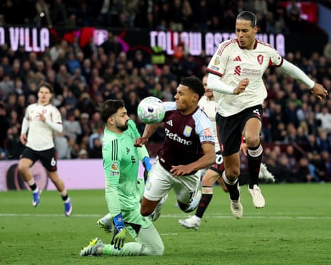 The ball hits Aston Villa's Ollie Watkins after a save from Liverpool's Giorgi Mamardashvili as Virgil van Dijk looks on.